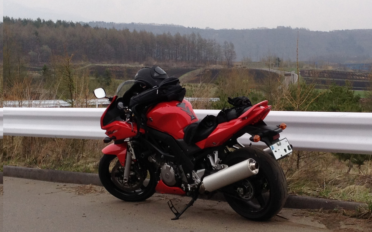 山並みを背景に停めた赤いスズキSV1000S